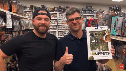 Two Men In A Store Holding A Box Of Muppets GIF