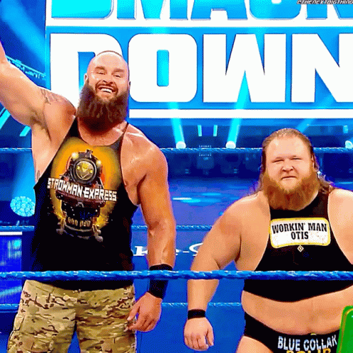 Two Men In A Wrestling Ring One Wearing A Shirt That Says Workin ' Man Otis GIF