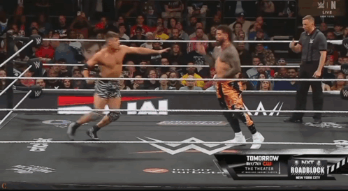 two men in a wrestling ring with a sign that says " tomorrow "