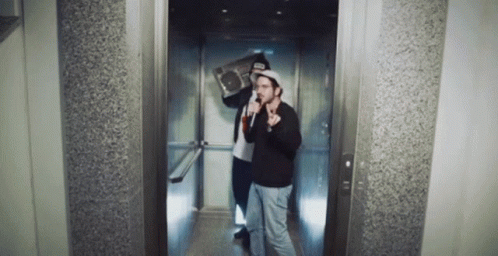 Two Men In An Elevator With One Holding A Boombox On His Shoulder GIF