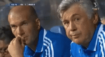 Two Men In Blue Shirts Are Watching A Soccer Game With The Number 3 On The Bottom Of The Screen GIF
