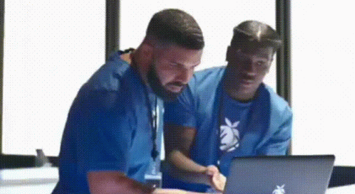 Two Men in Blue Shirts Looking at Laptop