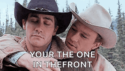 Two Men In Cowboy Hats Are Hugging Each Other With The Words `` Your The One In The Front '' Written Above Them . GIF