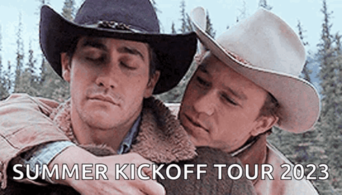 Two Men in Cowboy Hats Hugging in Forest
