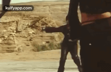 Two Men In Desert One Holding Gun GIF