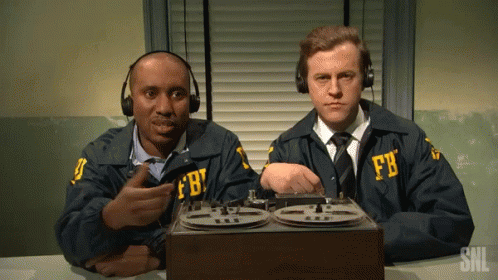 Two Men In Fbi Uniforms Sit At A Desk With A Tape Recorder GIF