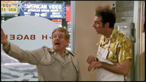 Two Men In Front Of An American Video Sign GIF