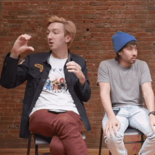 Two Men In Front Of Brick Wall One Wearing V V Shirt GIF