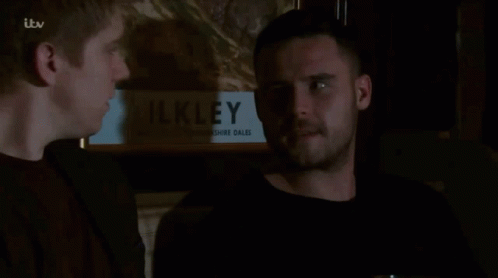 Two Men in Front of Painting Saying Ilkley