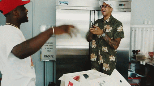 Two Men In Front Of Treats Sign GIF