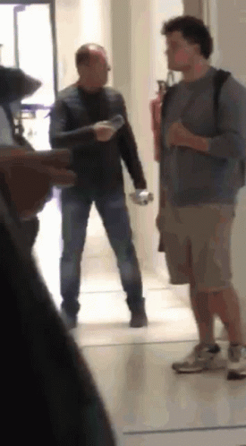 Two Men in Hallway One Holding Water Bottle