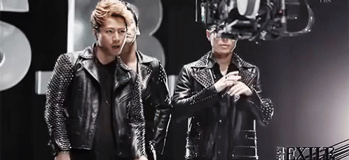 Two Men In Leather Jackets In Front Of Chandelier GIF