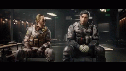 Two Men In Military Uniforms Are Sitting In Chairs In A Dark Room . GIF