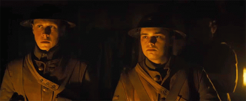 Two Men In Military Uniforms Are Standing Next To Each Other In The Dark GIF