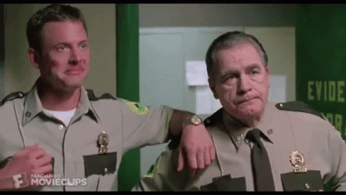 Two Men In Police Uniforms Are Standing Next To Each Other In A Room . GIF