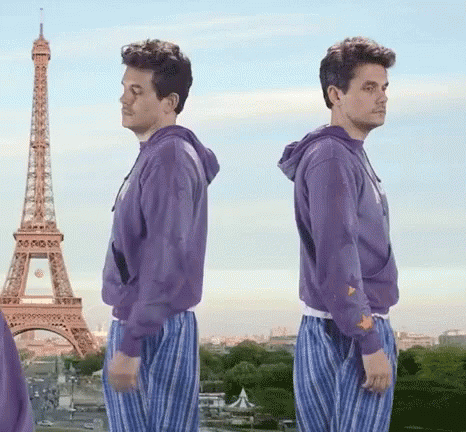 Two Men In Purple Sweatshirts Are Standing In Front Of The Eiffel Tower In Paris GIF