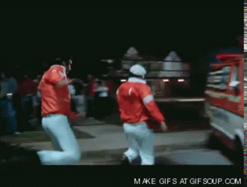 Two Men In Red Jackets Are Dancing In Front Of A Fire Truck That Says Make Gifs At Gif Soup.com GIF