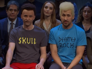 Two Men In Skull And Death Rock Shirts In Crowd GIF