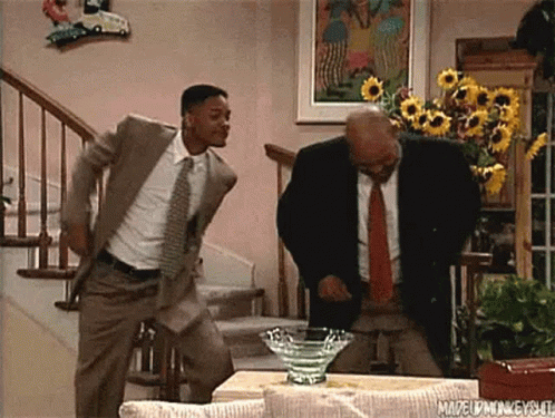 Two Men In Suits And Ties Are Dancing In A Living Room In Front Of Stairs . GIF