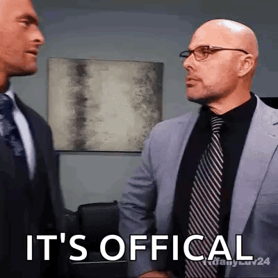 Two Men In Suits And Ties Are Shaking Hands And One Of Them Says It 'S Official GIF