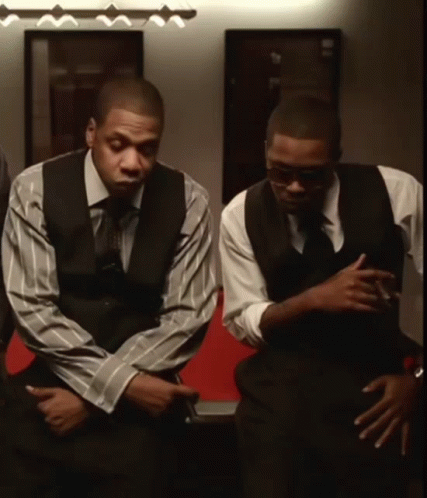 Two Men In Suits And Ties Are Sitting In A Room GIF