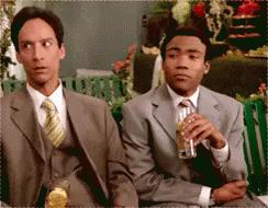 Two Men In Suits And Ties Are Sitting On A Bench Drinking Beer GIF
