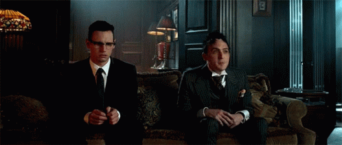 Two Men In Suits And Ties Are Sitting On A Couch And Clapping Their Hands . GIF