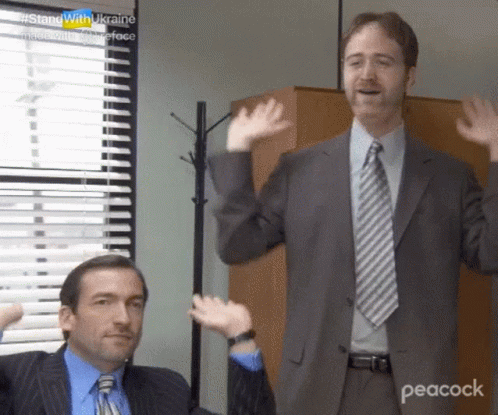 Two Men In Suits And Ties Are Standing In Front Of A Window And Waving Their Hands . GIF
