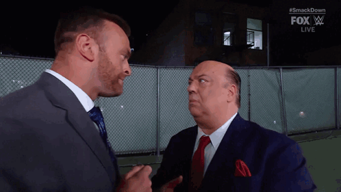 Two Men In Suits And Ties Are Standing Next To Each Other And Talking . GIF