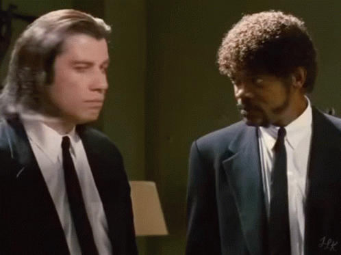 Two Men In Suits And Ties Are Standing Next To Each Other In A Room And Talking . GIF