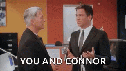 Two Men In Suits And Ties Are Standing Next To Each Other In An Office And Shaking Hands . GIF