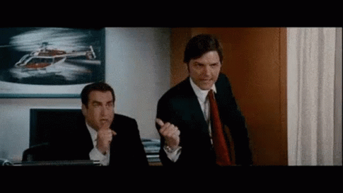 Two Men In Suits And Ties Are Standing Next To Each Other In An Office With A Helicopter In The Background . GIF