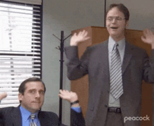 Two Men In Suits And Ties Are Waving Their Hands In A Room . GIF