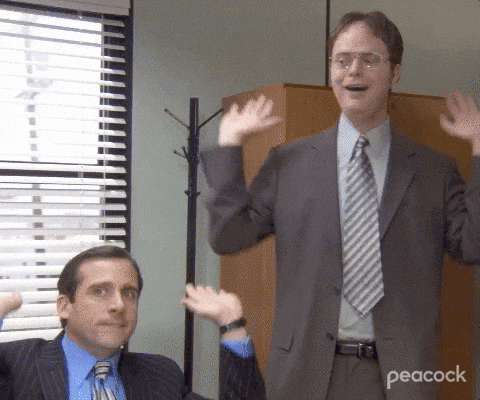 Two Men In Suits And Ties Are Waving Their Hands In Front Of A Window With Peacock Written On The Bottom Right Corner GIF