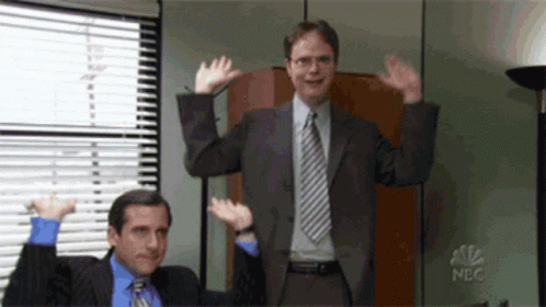 Two Men In Suits And Ties Are Waving Their Hands In The Air In Front Of A Nbc Logo GIF