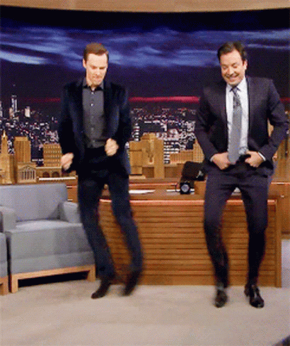 Two Men In Suits Are Dancing In Front Of A Desk GIF