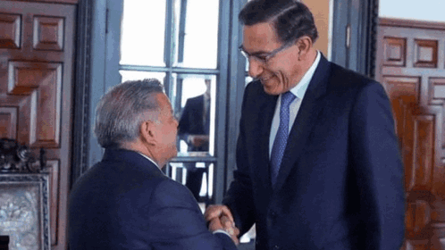 Two Men In Suits Are Shaking Hands And Smiling GIF