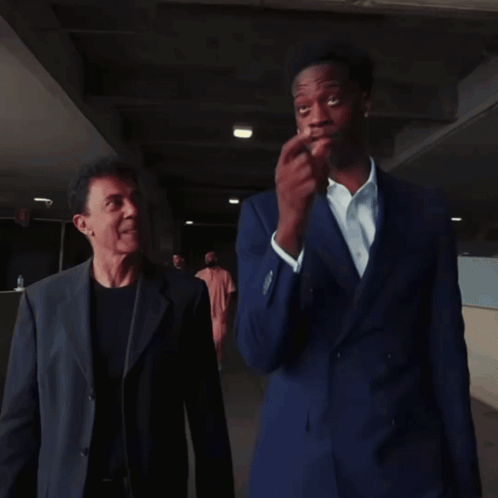 Two Men In Suits Are Standing Next To Each Other GIF