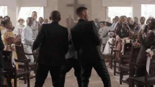 Two Men In Suits Are Walking Down A Church Aisle GIF