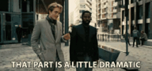 Two Men In Suits Are Walking Down A Street And One Of Them Is Saying That Part Is A Little Dramatic . GIF