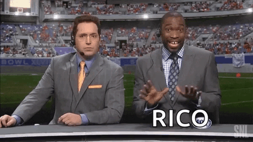 Two Men in Suits in Front of Stadium Rico