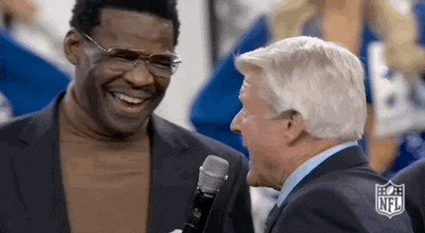 Two Men in Suits Laughing Into Microphone