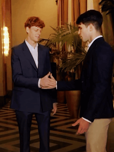 Two Men In Suits Shake Hands Near Plant GIF