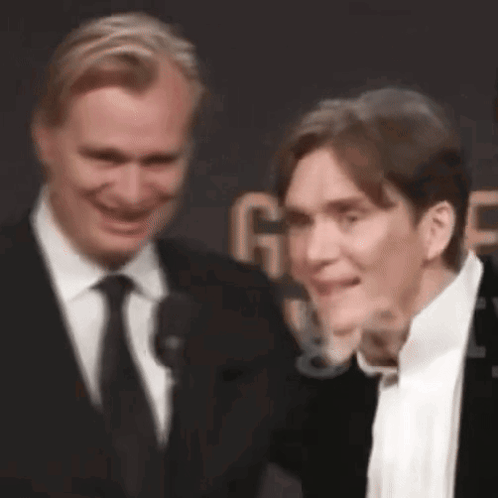 Two Men In Suits Smiling On Red Carpet GIF