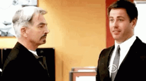 Two Men In Suits Talking In Office GIF