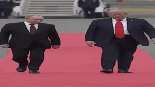 Two Men In Suits Walking On Red Carpet GIF