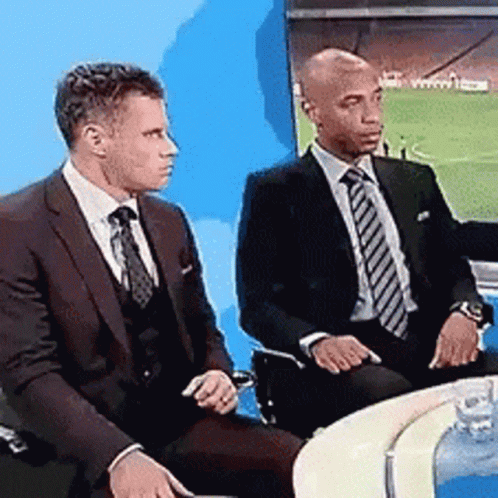 Two Men in Suits Watching TV at Table