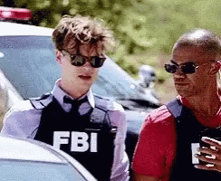Two Men in Sunglasses and FBI Vest in Front of Police Car