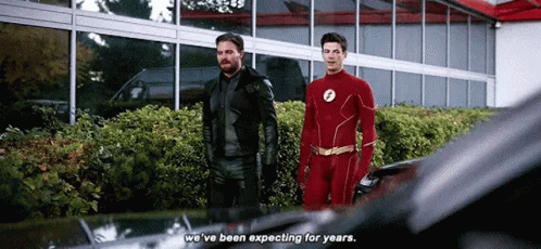 Two Men In Superhero Costumes Are Standing Next To Each Other And Talking . GIF