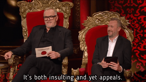 Two Men in Throne One Holding Card Saying Taskmaster